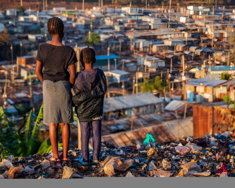 African little girls standing in trash and looking at houses in Kibera slum, Kenya, East Africa. Kibera is the largest slum in Nairobi, the largest urban slum in Africa, and the third largest in the world